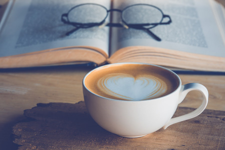 Cup of coffe with vintage old books on wooden deck tabletopの写真素材