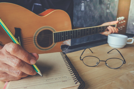 Young man composing the song with guitar on tableの写真素材
