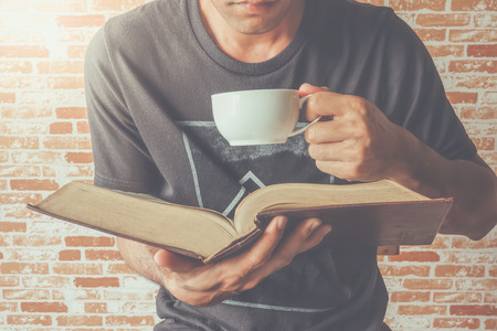A man read old book on tea or coffee timeの写真素材