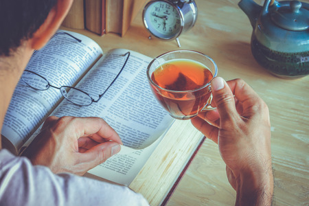 A man reading books and drinking teaの写真素材