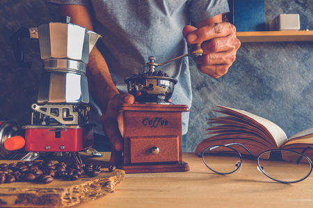 Roasted coffee bean in vintage grinder with coffee maker Moka pot on tableの写真素材