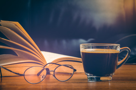 Cup of coffee with glasses and book on table in afternoon timeの写真素材