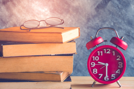 Education concept. Alarm clock with old books and eyeglassesの写真素材