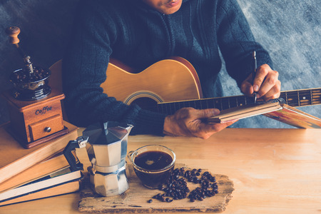 A young man composing music with coffee maker and black coffeeの写真素材