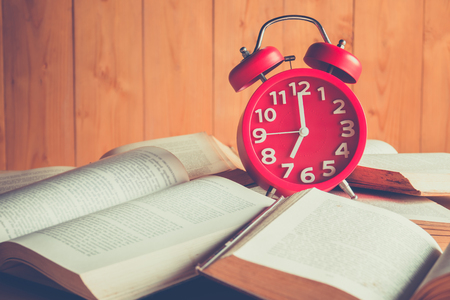Red alarm clock on stack old booksの写真素材