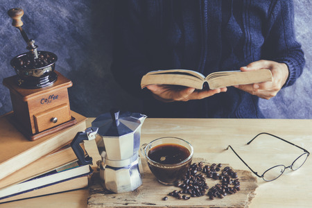 A man reading book with cup of coffee and coffee maker Moka potの写真素材