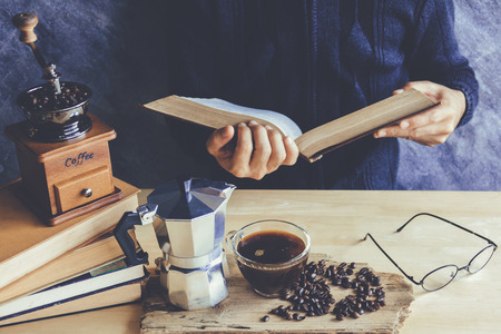 A man reading book with cup of coffee and coffee maker Moka potの写真素材