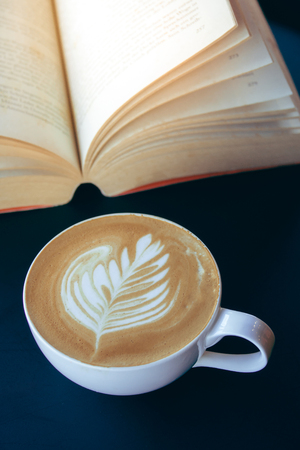 Cup of latte or cappuccino coffee with a book in coffee shopの写真素材