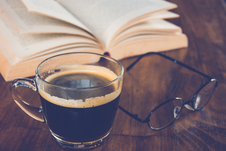 A cup of black coffee with book and glasses on table in coffee shopの写真素材