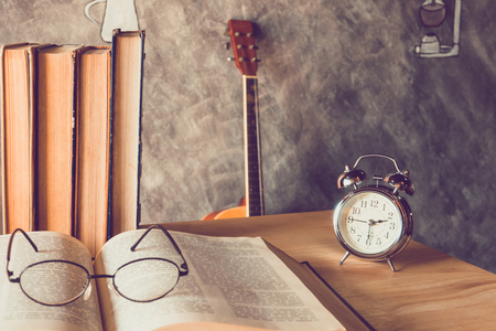 Alarm clock with old books on table with glasseの写真素材