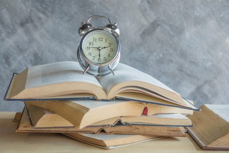 Retro alarm clock on open stack bookの写真素材