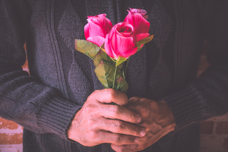 A man holding pink rosesの写真素材