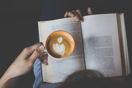 Top view of a girl reading book and drinking coffee , focus subjectの写真素材