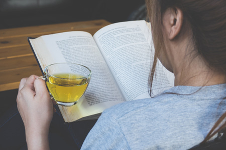 A girl reading book with a cup of green teaの写真素材