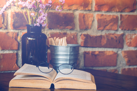 Reading glasses on table with open book in cafeの写真素材