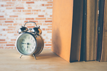 Retro alarm clock with row book on wood tableの写真素材