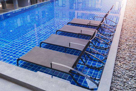 Chaise lounges in swimming poolの写真素材