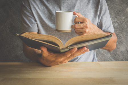 A man reading a book with drinking coffee or teaの写真素材