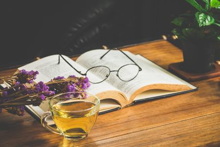 Tea time with reading book on table in cafeの写真素材