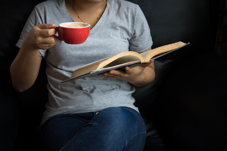 Young girl reading a book and drinking coffeeの写真素材