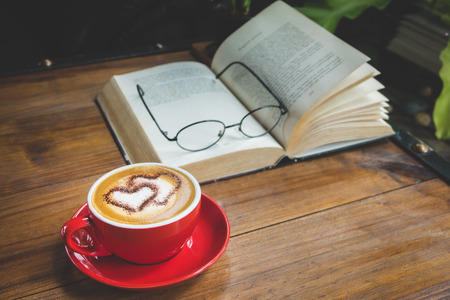 cup of latte or cappuccino coffee with a book in coffee shopの写真素材