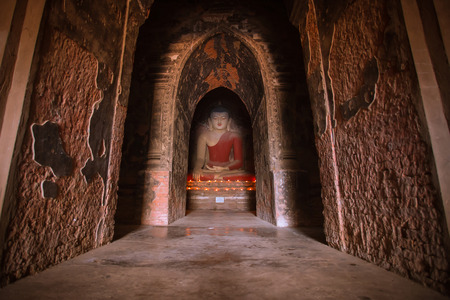 BAGAN, MYANMAR - Dec 12: Monk is praying with candles in front of Buddha statue inside pagoda on Dec 12, 2015 in Bagan. Monks with light and Buddha are highlighted of Baganのeditorial素材