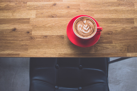 Coffee latte art on wooden table with leather seat in coffee shopの写真素材