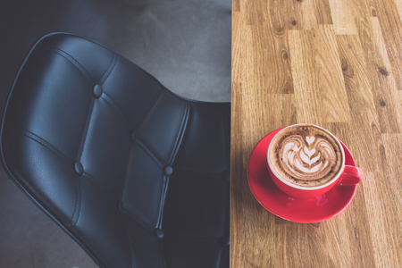 Coffee latte art on wooden table with leather seat in coffee shopの写真素材