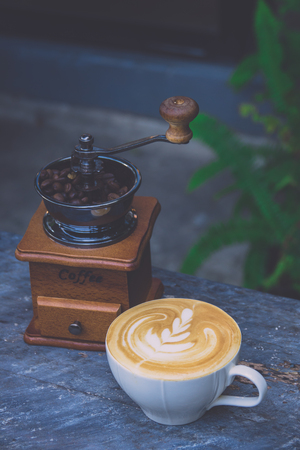 Coffee latte with vintage coffee grinder and coffee bean on tableの写真素材