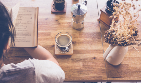 Young girl reading a book and drinking coffee, top viewの写真素材