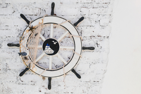 Old Ship Wheel (helm) on brick wall for decorationの写真素材