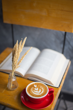 A cup of latte coffee with book on wood tableの写真素材