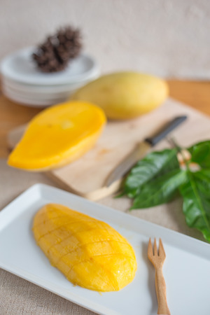 Fresh mango slice on white dish and mangos on wood plateの写真素材