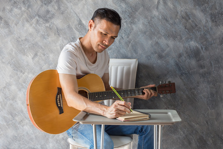 Young man composing the song with guitar on tableの写真素材