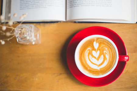 A cup of latte coffee with book on wood tableの写真素材