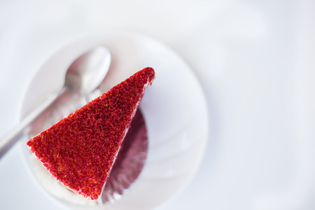 Red velvet cake on white dish with spoon on white background