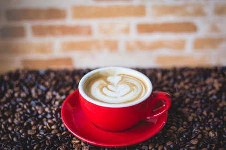 a red cup of coffee with coffee beanの写真素材