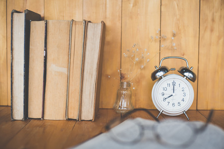 Alarm clock with old books on table . Vintage filterの写真素材