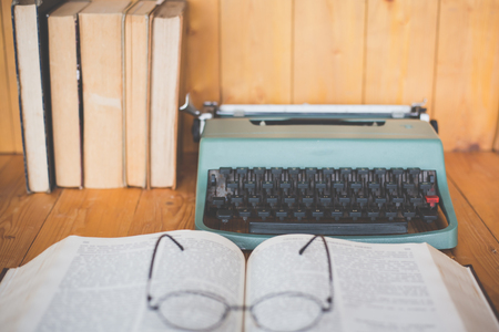 Retro typewriter and old vintage books on wooden table near empty wall backgroundの写真素材