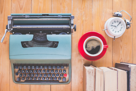 Old typewriter with a cup of coffee and books on wood table