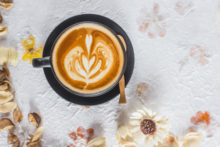 A Cup of hot latte art coffee on dried flower paper 