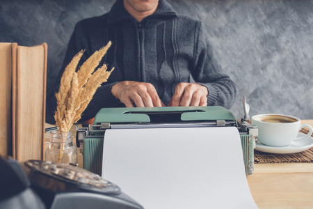 Hand of man working with typewriter and a cup of coffee in coffee shop