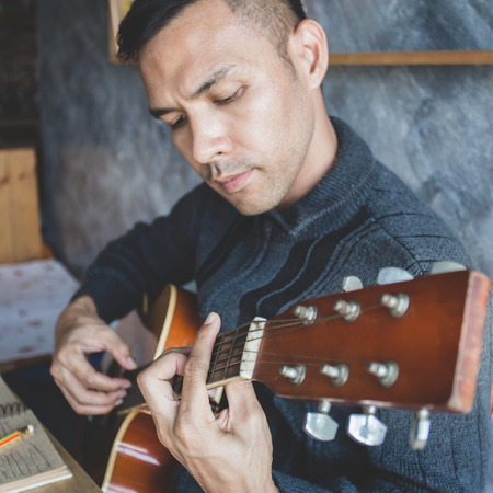Young man composing the song with guitar on tableの写真素材