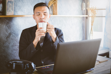 Young businessman with cup of coffee enjoying its aroma and tasteの写真素材