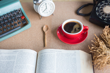 A cup of coffee with typewriter and alarm clock  and book on tableの写真素材
