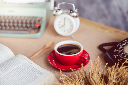 A cup of coffee with typewriter and alarm clock  and book on tableの写真素材