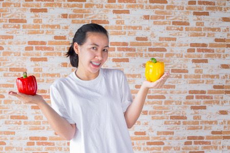 a beautiful girl with yellow and red pepper in the handsの写真素材