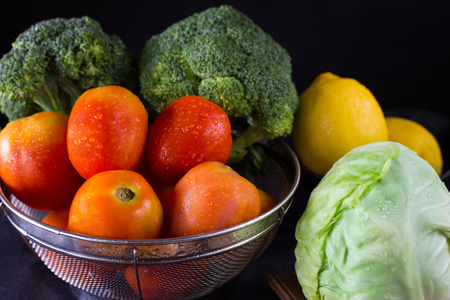 Fresh organic tomatoes and various vegetable with water drops on dark  backgroundの写真素材