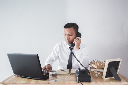 Business man working on laptop computer at home and calling on phone.の写真素材