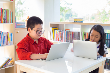 Young asian students using laptop working homework and learning in school libraryの写真素材